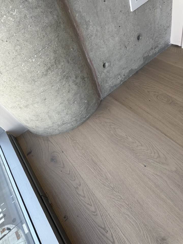 Finished light hardwood flooring across an open MGM project interior with large windows